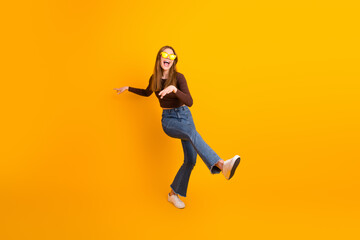 Obraz premium Energetic young woman with sunglass in casual wear posing on a vibrant yellow background in a fun and lively stance