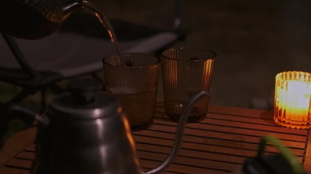 Pouring tea into charming glasses on a rustic table, softly lit by candles, creates a cozy atmosphere for gatherings