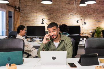 Focused businessman talking on phone and working on laptop in modern office