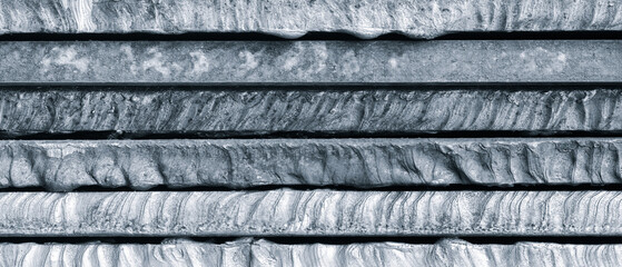 Stack of  thick heavy metal plates rusty uneven surface after laser cutting. plates stacked top each other, creating sense depth and texture. scene is somewhat dark industrial  background