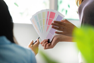 Design Consultation. Female designer showing color swatches to a colleague.