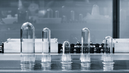 PETG plastic preforms for bottle making on the conveyor belt before the hot blow molding machine