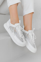 A close-up of fashionable white sneakers paired with light pants in a sleek, modern setting,...