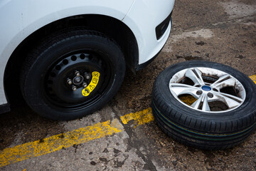 Replacing an emergency spare wheel with a regular one in a passenger car. Photo taken in natural...