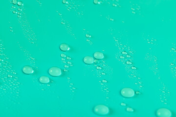 a smooth, light green surface covered with water droplets, a beautiful wet light green film in a...