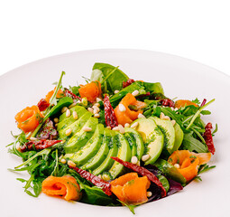 Fresh salad with avocado, smoked salmon, and herbs on a white plate