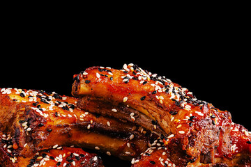 Tender barbecue ribs coated in sesame seeds on a dark background