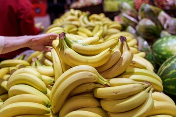 Ripe bananas displayed in a supermarket with a hand picking fruit