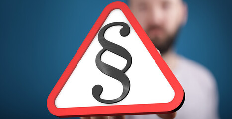 Stock photo of a hand holding a red triangle warning sign with a paragraph symbol.  Perfect for...
