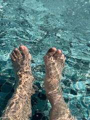 Cool summer feet in a refreshing turquoise pool. Perfect for travel, vacation, or summer themes.