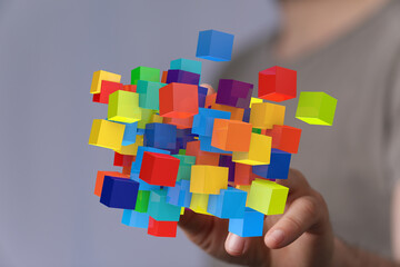 Obraz premium Abstract image of colorful cubes floating above a hand, representing innovation, creativity, and technology.
