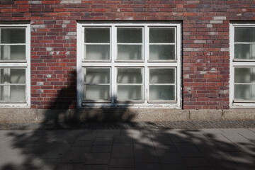 A straight-on, symmetrical view of the weathered facade of an old industrial or institutional building made of red brick.
