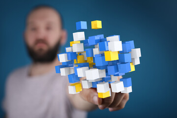 Abstract image of a man holding a cluster of colorful cubes, symbolizing data, technology, or...