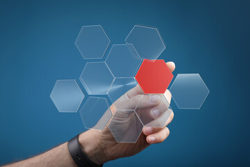 Abstract image of a hand selecting a red hexagon from a network of transparent hexagons.  Ideal for...