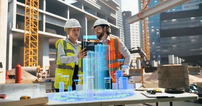 Diverse Architect Couple Working on a Construction Site, Using a Futuristic Augmented Reality Software with a Building 3D Blueprint Visualization. Male Engineer Interacting with the Hologram