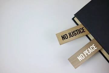 Wooden blocks printed with 'No Justice' and 'No Peace,' placed in a book as a bookmark.symbolizing equality, justice, and social activism.
