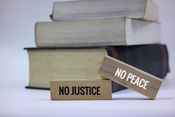 A stack of books with wooden blocks displaying 'No Justice No Peace', symbolizing equality, justice, and social activism.