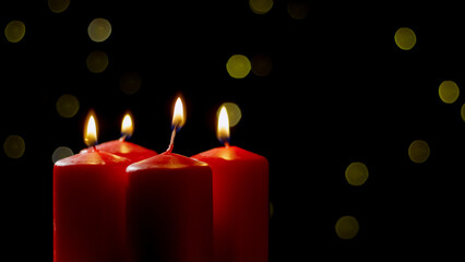 Four red candles burn brightly against a dark background, creating a cozy atmosphere filled with soft light.
