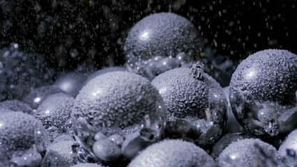 Shimmering silver Christmas ornaments are adorned with a thick layer of frost, creating a wintry atmosphere in a festive setting.