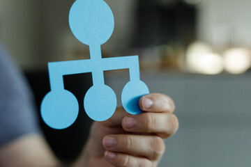 Image of a hand holding a paper hierarchy chart.  Illustrates team structure, organization, and...