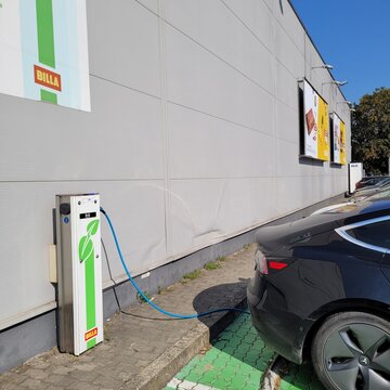 Senec, Slovakia - Sep 3, 2024: A static shot of a solid black Tesla Model 3 dual motor charging at the Billa AC charging station in a sunny summer day. Selective focus
