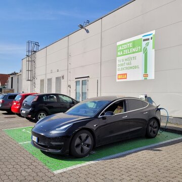 Senec, Slovakia - Sep 3, 2024: A static shot of a solid black Tesla Model 3 dual motor charging at the Billa AC charging station in a sunny summer day. Selective focus