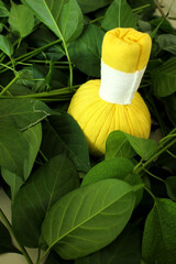 Yellow Herbal Compress Ball  placed on Green Leaves for Thai Spa, Ayurvedic Massage, and Thai...