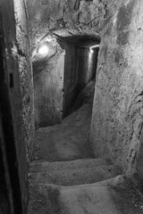 Mysterious descent into an ancient underground tunnel showcasing weathered stone walls and dimly...