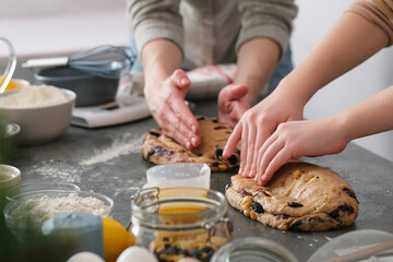 Hands shaping loaves of Christmas Bread or stollen cake are arranged on a table in a kitchen....
