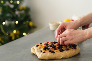 Hand puts dried fruits into brown raw dough in a cozy kitchen in a cozy atmosphere. The baker is...
