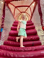 Fillette de 3 ans montant un filet de jeu rouge