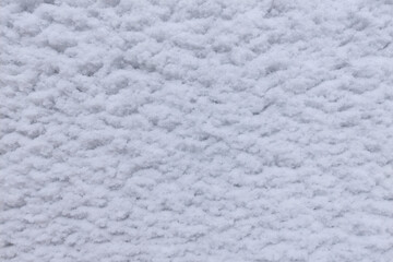 Snow flakes stuck in the form of waves on a white metal sheet.