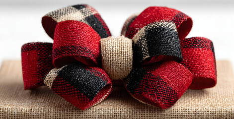 Red, white and black plaid Christmas gift bow and ribon. Wrapped box layout islated on a white backgroun.