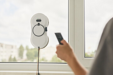 Robotic window cleaner being controlled by human hand, streamlining home maintenance with...