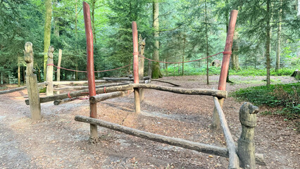 Wooden posts with red rope in forest adventure playground, natural outdoor fitness equipment for balance training, eco-friendly recreation, exercise, inspired gatherings, sustainable lifestyle in