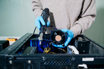 Closeup of technician in gloves holding CPU cooler and heat gun over desktop PC. Ideal image for...