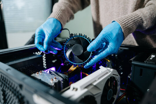 Closeup of technician in gloves holding CPU cooler and heat gun over desktop PC. Ideal image for computer repair, cooling system, and hardware