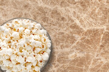 A bowl of tasty salt popcorn on desk background,