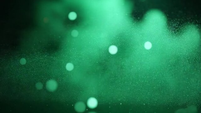 Elegant defocused green dust particles over dark background. Event game trailer titles cinematic concert stage background