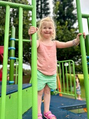 Fillette de 3 ans joyeuse sur un jeu d’escalade vert