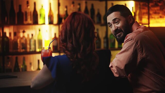 Smiling man talking with red-haired woman in bar, looking for one night stand