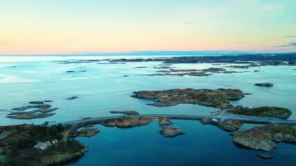 An aerial drone shot capturing the iconic Atlantic Ocean Road Atlanterhavsveien in Norway during a beautiful sunset, showcasing the bridges connecting small islands and the vast ocean surrounding them - Powered by Adobe