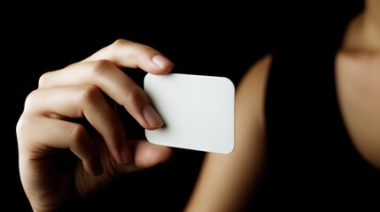 hand elegantly holds a blank white card in a dark environment, showcasing an inviting space for creativity or message expression without distractions