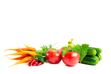 Fresh young carrots, tomatoes, cucumbers and hot chili peppers with leaves isolated on white.