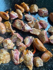 Pieces of meat cooking in a frying pan