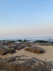 Ocean waves crashing on a sandy beach at sunset with a pastel sky