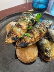 Two grilled sardines on potatoes served on a plate
