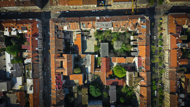 Aerial view of a vibrant courtyard bursting with green foliage, nestled amidst the red-tiled roofs of buildings, a stark contrast to the surrounding urban landscape, Zagreb, Zagreb, Croatia.
