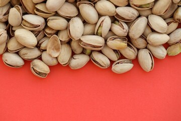 Tasty unpeeled pistachios on bright red background, top view flat lay background pattern