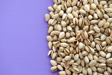 Tasty unpeeled pistachios on bright purple background, top view flat lay background pattern